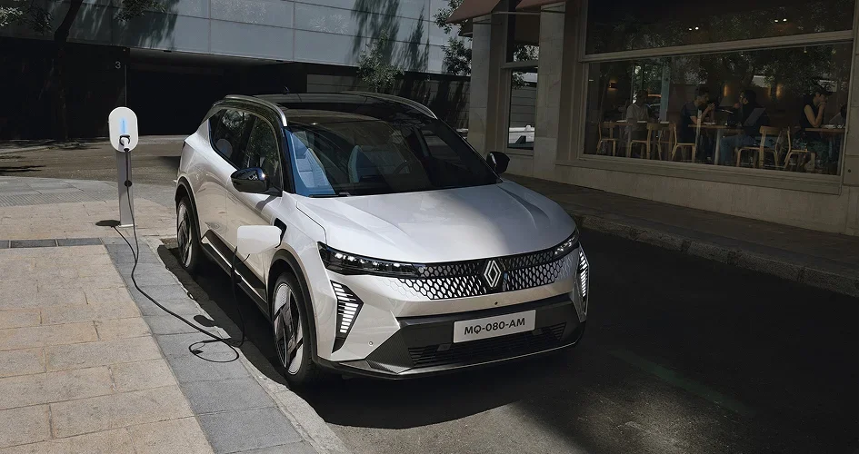 SUV électrique Renault gris en charge sur une borne de recharge en ville.